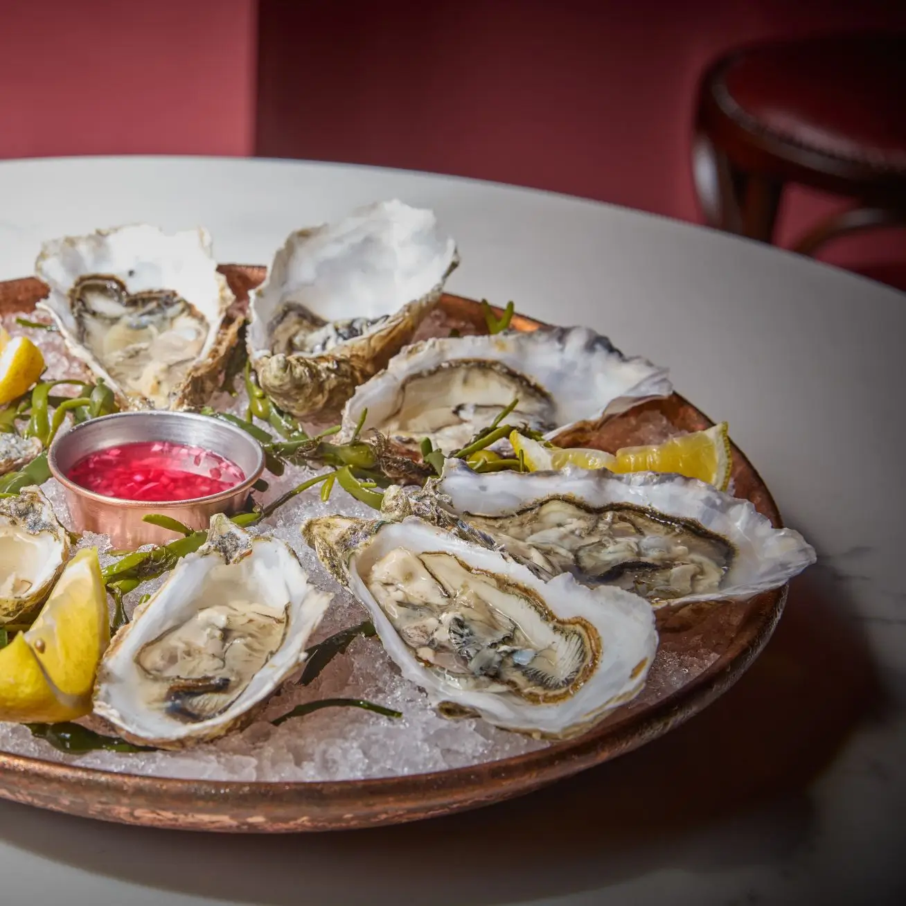 Home 3 A copper platter of freshly shucked Irish oysters on a bed of crushed ice, served with lemon wedges and a vibrant mignonette sauce.
